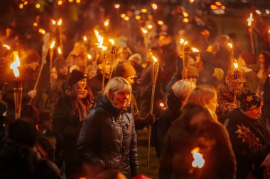 11 Kasım 'da Lpla Günü' nü kutlamak için Valmiera 'da bir meşale geçidi düzenlendi. İnsanlar ellerinde yanan meşaleler ve ulusal bayraklar tutuyor.
