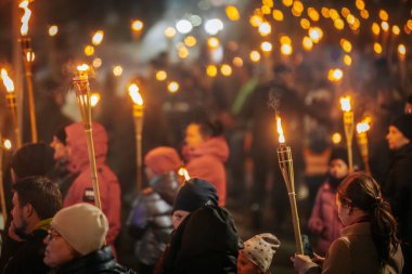 11 Kasım 'da Lpla Günü' nü kutlamak için Valmiera 'da bir meşale geçidi düzenlendi. İnsanlar ellerinde yanan meşaleler ve ulusal bayraklar tutuyor.