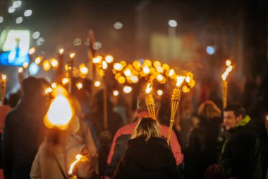 11 Kasım 'da Lpla Günü' nü kutlamak için Valmiera 'da bir meşale geçidi düzenlendi. İnsanlar ellerinde yanan meşaleler ve ulusal bayraklar tutuyor.