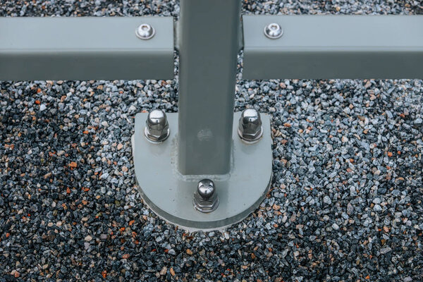 Низкоугольный вид на современный подвесный мост, демонстрирующий конструктивные балки и кабели. Мост охватывает природный ландшафт с высокими вечнозелеными деревьями и облачным небом на заднем плане.