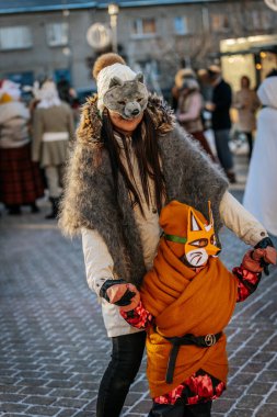 Bir grup kostümlü katılımcı, geleneksel kıyafet ve festival maskeleriyle Kış Gündönümünü kutluyor, kültürel mirası ve mevsimsel keyfi ele geçiriyorlar. 12.21.2024 Balvi, Letonya