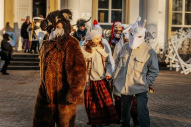 Bir grup kostümlü katılımcı, geleneksel kıyafet ve festival maskeleriyle Kış Gündönümünü kutluyor, kültürel mirası ve mevsimsel keyfi ele geçiriyorlar. 12.21.2024 Balvi, Letonya