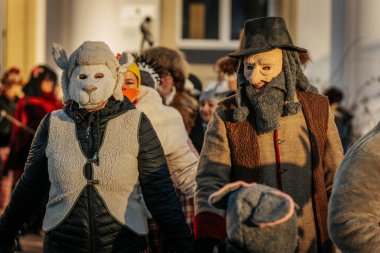 Bir grup kostümlü katılımcı, geleneksel kıyafet ve festival maskeleriyle Kış Gündönümünü kutluyor, kültürel mirası ve mevsimsel keyfi ele geçiriyorlar. 12.21.2024 Balvi, Letonya