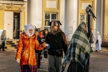 Bir grup kostümlü katılımcı, geleneksel kıyafet ve festival maskeleriyle Kış Gündönümünü kutluyor, kültürel mirası ve mevsimsel keyfi ele geçiriyorlar. 12.21.2024 Balvi, Letonya