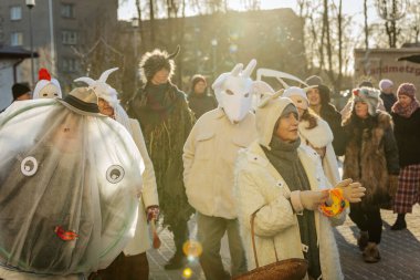 Bir grup kostümlü katılımcı, geleneksel kıyafet ve festival maskeleriyle Kış Gündönümünü kutluyor, kültürel mirası ve mevsimsel keyfi ele geçiriyorlar. 12.21.2024 Balvi, Letonya