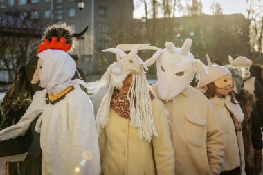 Bir grup kostümlü katılımcı, geleneksel kıyafet ve festival maskeleriyle Kış Gündönümünü kutluyor, kültürel mirası ve mevsimsel keyfi ele geçiriyorlar. 12.21.2024 Balvi, Letonya