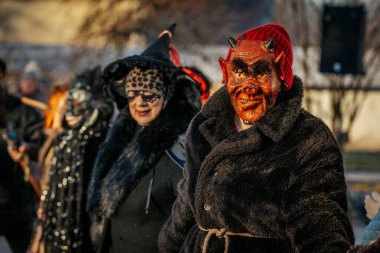 Bir grup kostümlü katılımcı, geleneksel kıyafet ve festival maskeleriyle Kış Gündönümünü kutluyor, kültürel mirası ve mevsimsel keyfi ele geçiriyorlar. 12.21.2024 Balvi, Letonya