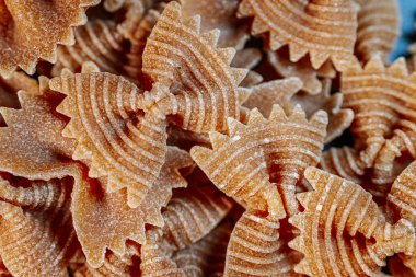 Kuru papyon şeklindeki, kıvrık desenli makarnanın yakın çekimi. Karmaşık desenler onun eşsiz tasarımını vurgular, onu mutfak temalı görseller ve yemek kavramları için ideal kılar..