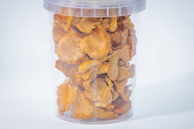 Dondurulmuş mantar mantarlarıyla dolu plastik bir kap. Altın renklerini ve dokulu detaylarını sergiliyor. Aşçılık kullanımı veya gurme depolama için ideal.