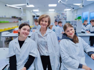 Bir grup öğrenci ve öğretmenleri tam teçhizatlı bir kimya laboratuvarında laboratuvar önlüğü giyip bilimsel deneyler ve çalışmalar yapıyorlar. parlak akademik ortam