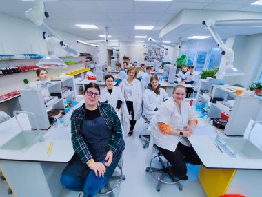 Bir grup öğrenci ve öğretmenleri tam teçhizatlı bir kimya laboratuvarında laboratuvar önlüğü giyip bilimsel deneyler ve çalışmalar yapıyorlar. parlak akademik ortam