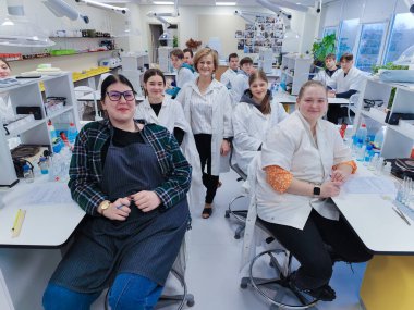 Bir grup öğrenci ve öğretmenleri tam teçhizatlı bir kimya laboratuvarında laboratuvar önlüğü giyip bilimsel deneyler ve çalışmalar yapıyorlar. parlak akademik ortam