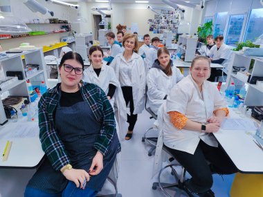 Bir grup öğrenci ve öğretmenleri tam teçhizatlı bir kimya laboratuvarında laboratuvar önlüğü giyip bilimsel deneyler ve çalışmalar yapıyorlar. parlak akademik ortam