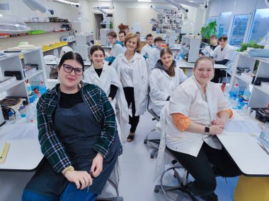 Bir grup öğrenci ve öğretmenleri tam teçhizatlı bir kimya laboratuvarında laboratuvar önlüğü giyip bilimsel deneyler ve çalışmalar yapıyorlar. parlak akademik ortam