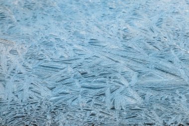 Karmaşık desenli çatlamış buz oluşumları donmuş bir yüzeyi kaplıyor. Keskin, pürüzsüz kenarlar pürüzsüz, yansıtıcı dokularla tezat oluşturarak büyüleyici bir kış sahnesi yaratıyor..