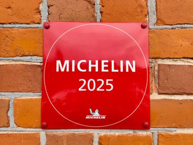 Michelin 2025 plaketi tuğla duvarda, Michelin Rehberi 'ndeki restoranın tanındığını gösteriyor. Prestijli notta aşçılık mükemmelliği ve kalitesi vurgulanıyor. 02.13.2025 Ligatne, Letonya