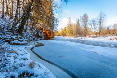 Üzerinde Sprenu iezis yazan, kısmen karla kaplı kırmızı kumtaşı bir uçurum. Kaya yüzeyinde doğal desenler ve oyulmuş yazıtlar var..
