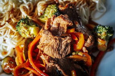 Taze sebzeler, erişteler, soslar ve soslarla dolu bir masa yemek kursu için hazırlandı. Eldivenin katılımcıları arka plandaki malzemeleri hazırlarlar..