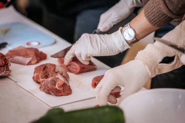 Taze sebzeler, erişteler, soslar ve soslarla dolu bir masa yemek kursu için hazırlandı. Eldivenin katılımcıları arka plandaki malzemeleri hazırlarlar..