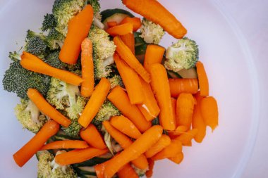 Taze doğranmış havuç, brokoli ve bambu filizleriyle dolu bir kasenin yakın çekimi. Canlı turuncu ve yeşil renkler taze malzemelerin altını çiziyor, pişirmeye ya da servis etmeye hazır..