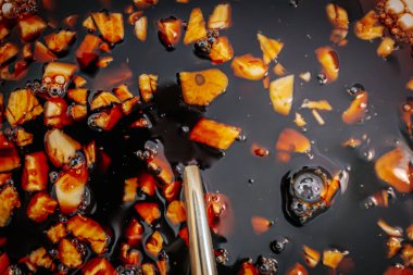 Bir kâsede doğranmış sarımsakla karıştırılmış teriyaki sosu. Yüzen sarımsak parçaları ve baloncuklarla kaplı koyu, parlak sıvı zengin, lezzetli bir doku yaratır..