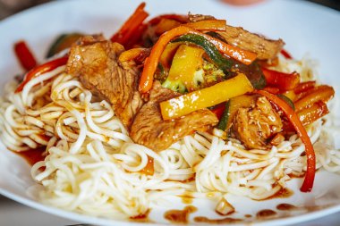 Kırmızı dolmalık biber, brokoli ve kabak da dahil olmak üzere sebzeli ızgara sığır eti. Lezzetli bir sosta erişteyle servis ediliyor. Lezzetli ve renkli bir Asya yemeği..