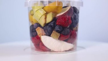A transparent jar filled with a colorful assortment of freeze-dried fruits and vegetables, including blueberries, cranberries, raspberries, apple slices, pumpkin cubes, and more.
