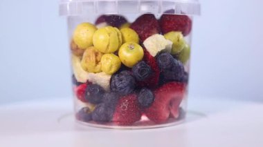 A transparent jar filled with a colorful assortment of freeze-dried fruits and vegetables, including blueberries, cranberries, raspberries, apple slices, pumpkin cubes, and more.