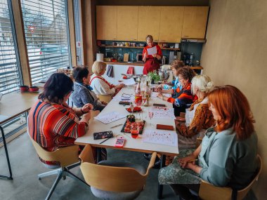 A group of people attends a Chinese cooking master class, led by a woman in a traditional outfit. The table is set with ingredients, knives, and red Chinese lanterns.