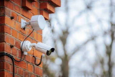 Derin mavi bir duvara monte edilmiş mavi koruyucu kapaklı modern bir kubbe güvenlik kamerası. Kameranın yansıtıcı yüzeyi, güvenlik ve gözetlemeyi sembolize ederek çevresini yakalıyor..