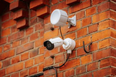 Derin mavi bir duvara monte edilmiş mavi koruyucu kapaklı modern bir kubbe güvenlik kamerası. Kameranın yansıtıcı yüzeyi, güvenlik ve gözetlemeyi sembolize ederek çevresini yakalıyor..