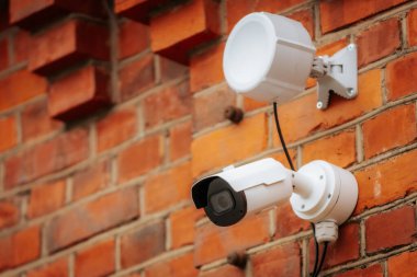 Derin mavi bir duvara monte edilmiş mavi koruyucu kapaklı modern bir kubbe güvenlik kamerası. Kameranın yansıtıcı yüzeyi, güvenlik ve gözetlemeyi sembolize ederek çevresini yakalıyor..