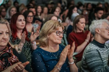 Bir orkestra şefinin yönetiminde sahnedeki canlı performansları senkronize ve tutkulu bir şekilde müzik kağıtları tutan bir koro şefinin yönetiminde sahneye çıkıyor. 03.15.2025 Valmiera, Letonya