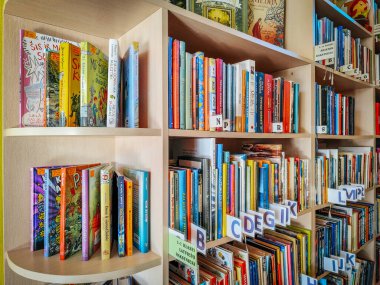 Renkli kitaplıkları olan, edebiyatla dolu, kolay erişim için düzgünce düzenlenmiş bir kütüphane. Davet edilen alan öğrenmeyi, okumayı ve keşfi teşvik ediyor. 03.15.2025 Staicele, Letonya