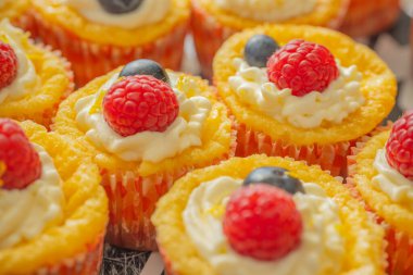 Krem şantili, taze ahududu ve parlak kağıt kaplamalı yaban mersinli lezzetli kekler. Parlak renkler ve yumuşak dokularla mükemmel şekilde detaylandırılmış..