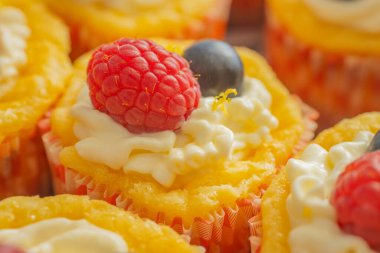 Krem şantili, taze ahududu ve parlak kağıt kaplamalı yaban mersinli lezzetli kekler. Parlak renkler ve yumuşak dokularla mükemmel şekilde detaylandırılmış..