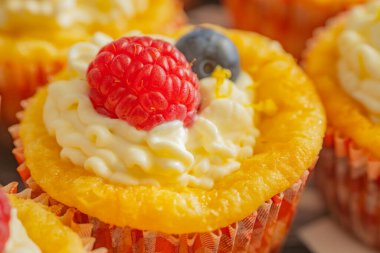 Krem şantili, taze ahududu ve parlak kağıt kaplamalı yaban mersinli lezzetli kekler. Parlak renkler ve yumuşak dokularla mükemmel şekilde detaylandırılmış..