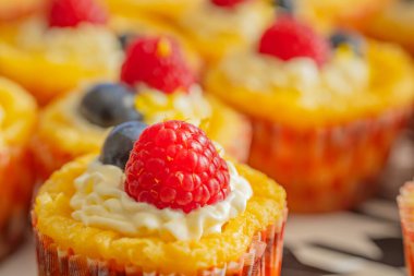 Krem şantili, taze ahududu ve parlak kağıt kaplamalı yaban mersinli lezzetli kekler. Parlak renkler ve yumuşak dokularla mükemmel şekilde detaylandırılmış..