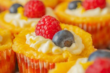 Krem şantili, taze ahududu ve parlak kağıt kaplamalı yaban mersinli lezzetli kekler. Parlak renkler ve yumuşak dokularla mükemmel şekilde detaylandırılmış..