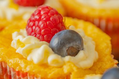 Krem şantili, taze ahududu ve parlak kağıt kaplamalı yaban mersinli lezzetli kekler. Parlak renkler ve yumuşak dokularla mükemmel şekilde detaylandırılmış..