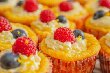 Krem şantili, taze ahududu ve parlak kağıt kaplamalı yaban mersinli lezzetli kekler. Parlak renkler ve yumuşak dokularla mükemmel şekilde detaylandırılmış..