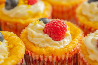 Krem şantili, taze ahududu ve parlak kağıt kaplamalı yaban mersinli lezzetli kekler. Parlak renkler ve yumuşak dokularla mükemmel şekilde detaylandırılmış..
