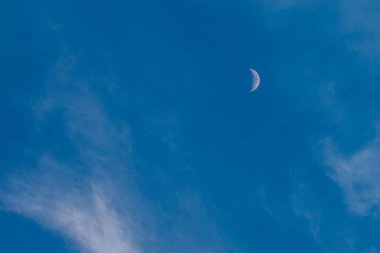 Soluk bir hilal, narin, ince bulutların arasından sakin mavi bir gökyüzünde belirir. Rüya gibi ve ruhani bir atmosfer yaratır..