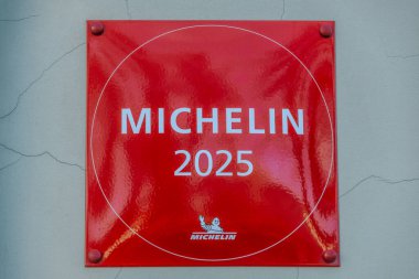 Michelin logosu ve Bibendum karakterinin yer aldığı kırmızı Michelin 2025 plaketinin yakın çekimi Michelin Rehberi tarafından tanındığını gösteriyor. 04.03.2025 Valmiera, Letonya