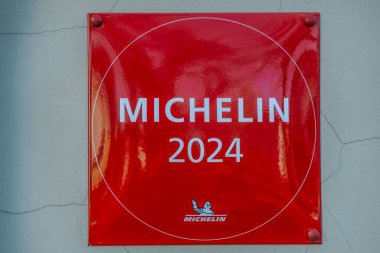 Michelin logosu ve Bibendum karakterinin yer aldığı kırmızı Michelin 2025 plaketinin yakın çekimi Michelin Rehberi tarafından tanındığını gösteriyor. 04.03.2025 Valmiera, Letonya