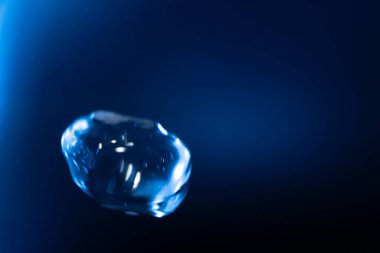 Parlayan, şeffaf mavi bir balon koyu mavi bir arkaplan üzerinde yüzer, yansımalar ve ışık çizgileri fütüristik ve sürrealist bir etki yaratır. Kopyalama alanı içerir.