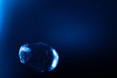 Parlayan, şeffaf mavi bir balon koyu mavi bir arkaplan üzerinde yüzer, yansımalar ve ışık çizgileri fütüristik ve sürrealist bir etki yaratır. Kopyalama alanı içerir.