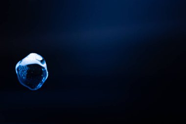 Parlayan, şeffaf mavi bir balon koyu mavi bir arkaplan üzerinde yüzer, yansımalar ve ışık çizgileri fütüristik ve sürrealist bir etki yaratır. Kopyalama alanı içerir.