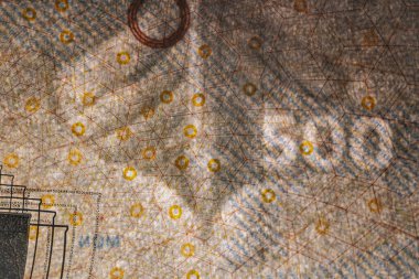 Tahta bir yüzeye yerleştirilmiş köprü çizimleri ve güvenlik unsurlarının yer aldığı Danimarka 'dan gelen 500 DKK banknotunun ayrıntılı bir görüntüsü.