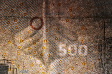 Tahta bir yüzeye yerleştirilmiş köprü çizimleri ve güvenlik unsurlarının yer aldığı Danimarka 'dan gelen 500 DKK banknotunun ayrıntılı bir görüntüsü.